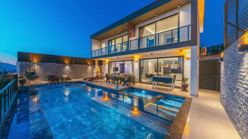 Maison moderne au crépuscule avec appliques murales allumées autour de la terrasse et de la piscine
